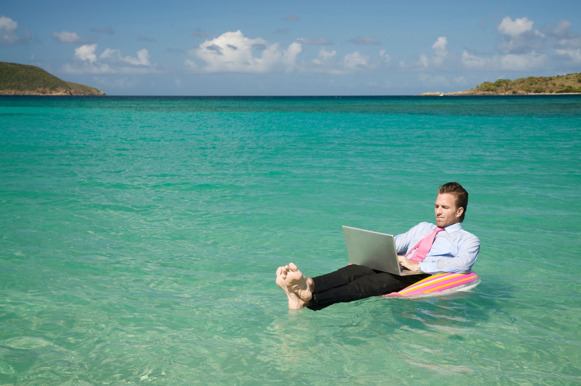 Businessman Floating Outdoors in Tropical Sea Working on Laptop